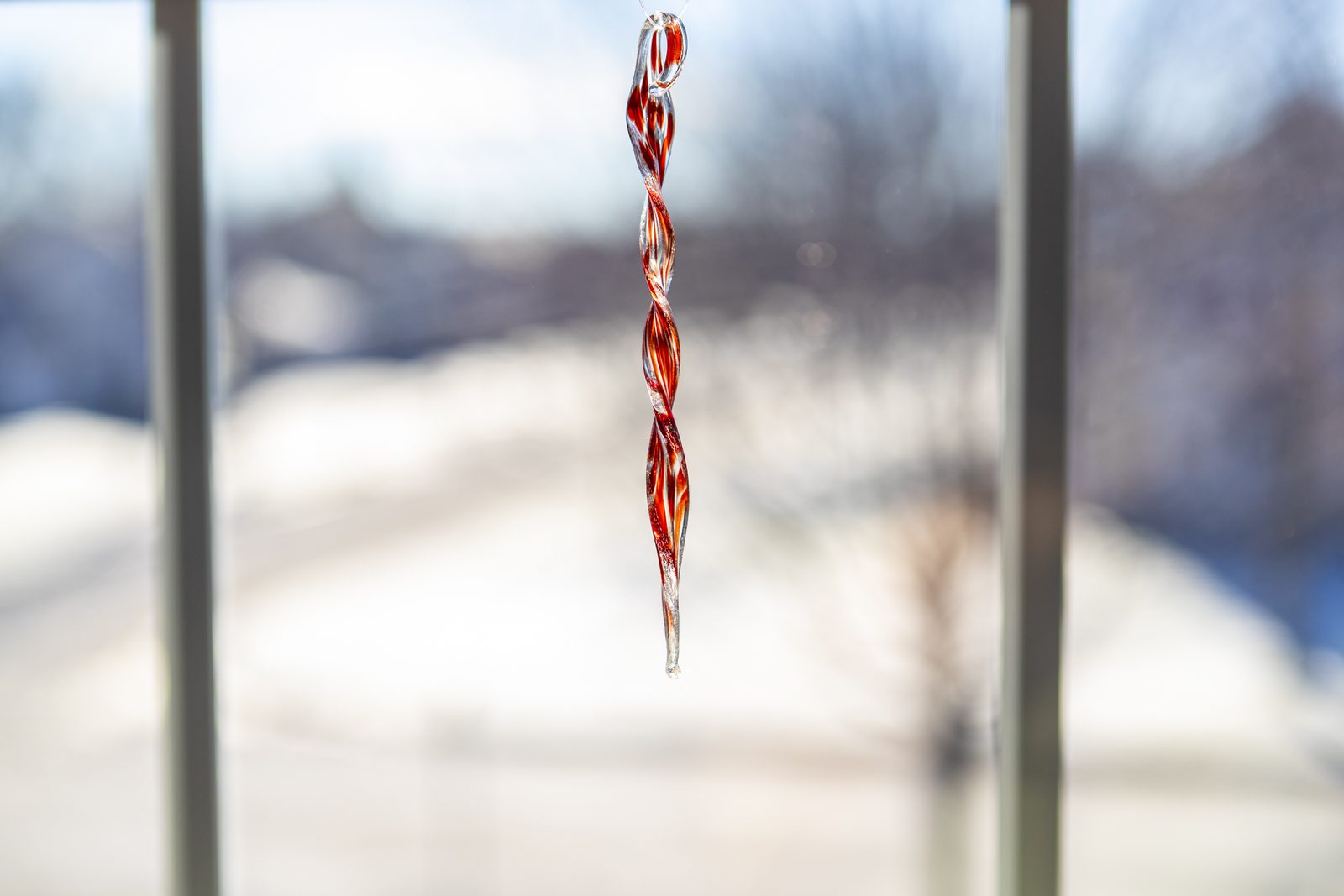 A red twisted glass suncatcher hanging in a sunny window