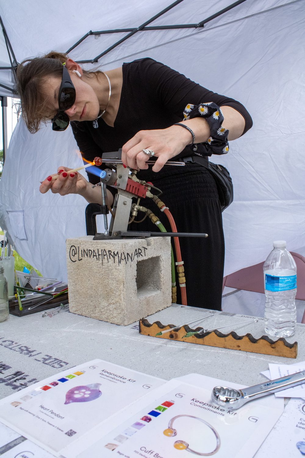 Linda Harman at her torch under an event tent, with guests' color choices laid out on the table