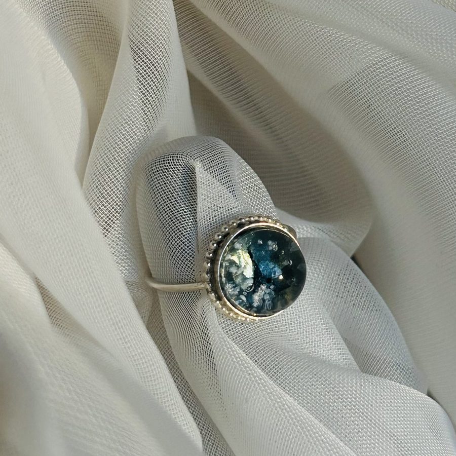 A silver bezel ring with blue glass resting on white tulle