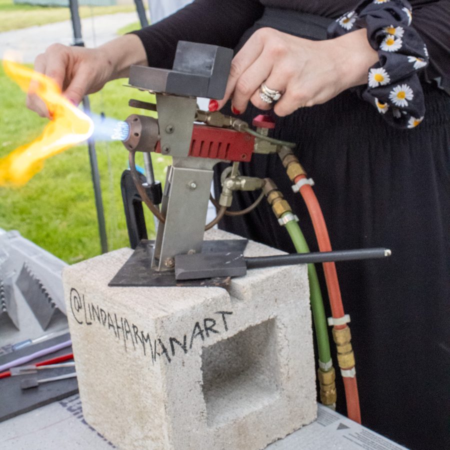 The torch flame at an outdoor event, set up on a block stamped with Linda Harman Art