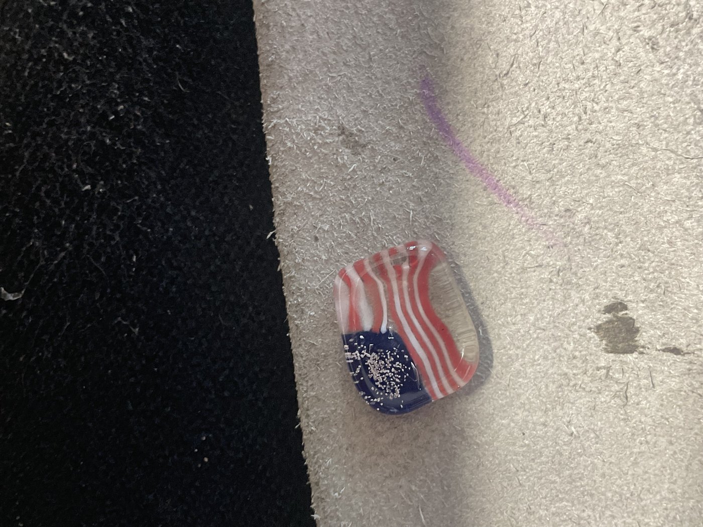 A single handmade flag glass piece resting on the studio bench