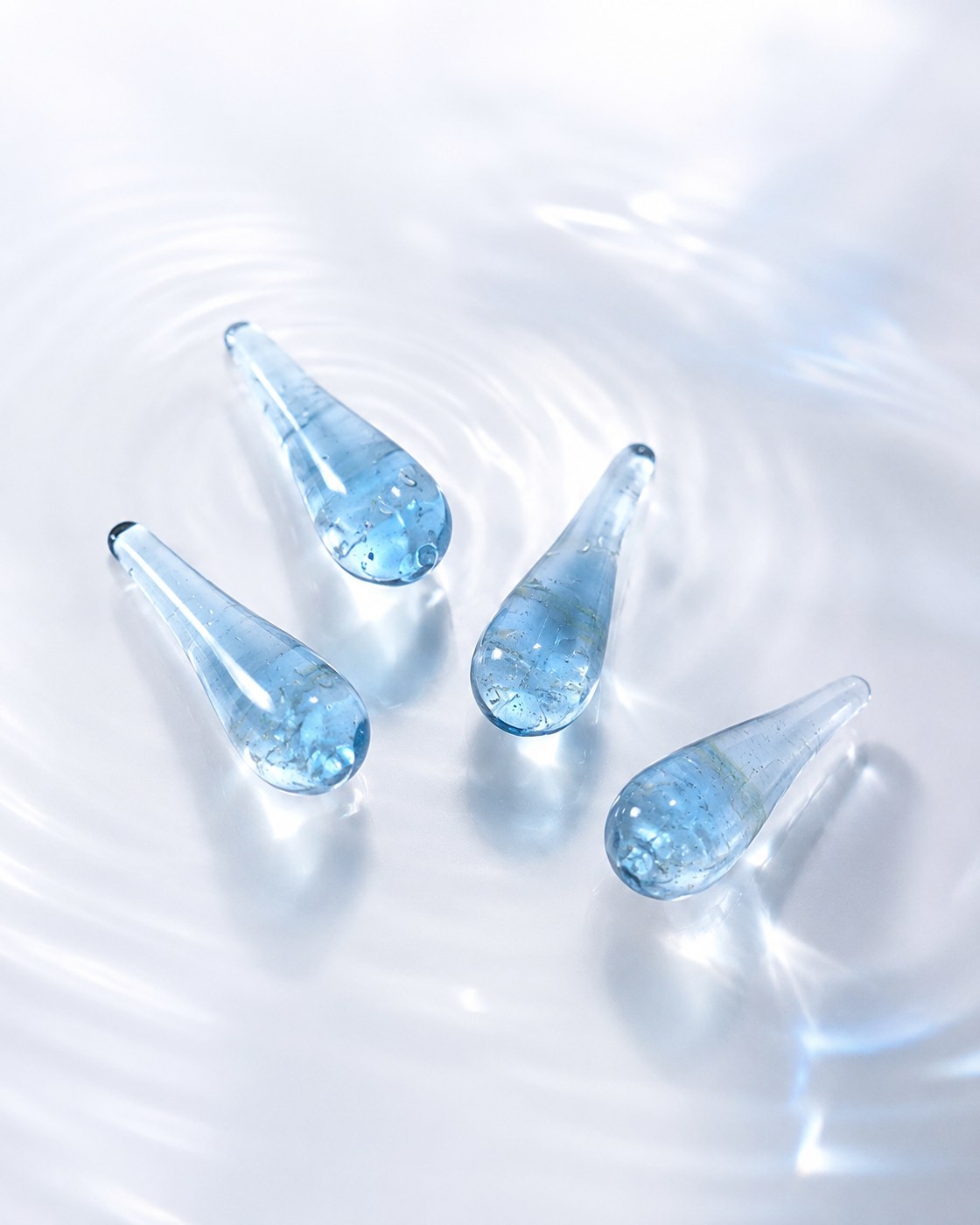 Four small glass remembrance droplets resting in still water